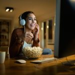 Mulher feliz comendo pipoca e assistindo filme no PC